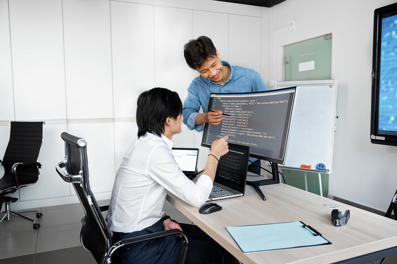The Art of Drawing Readers In: Your attractive post title goes here Two young professionals collaborating at a desk with laptops and monitors in a modern office setting.